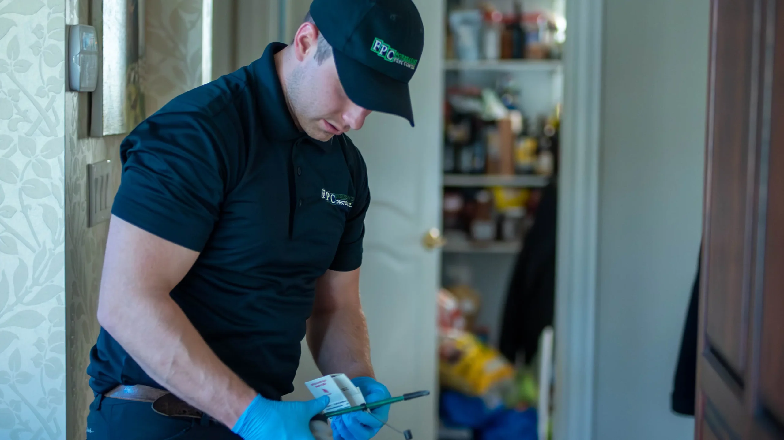 Professional Pest Control - Forbearance Pest Control - technician in blue uniform treating a pantry in the kitchen